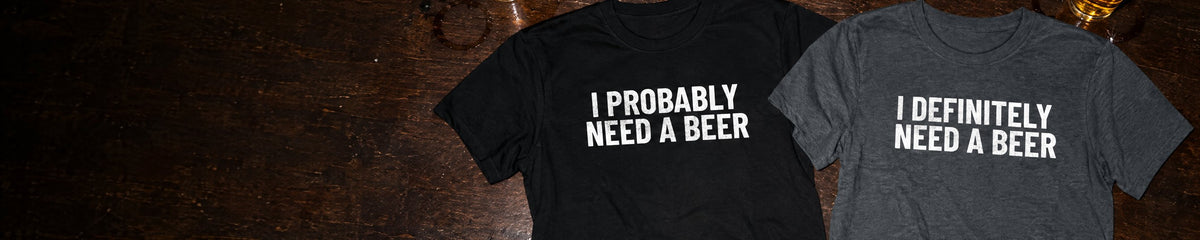 I Probably Need A Beer and I Definitely Need A Beer t-shirts laid on a bar top next to two pints of beer